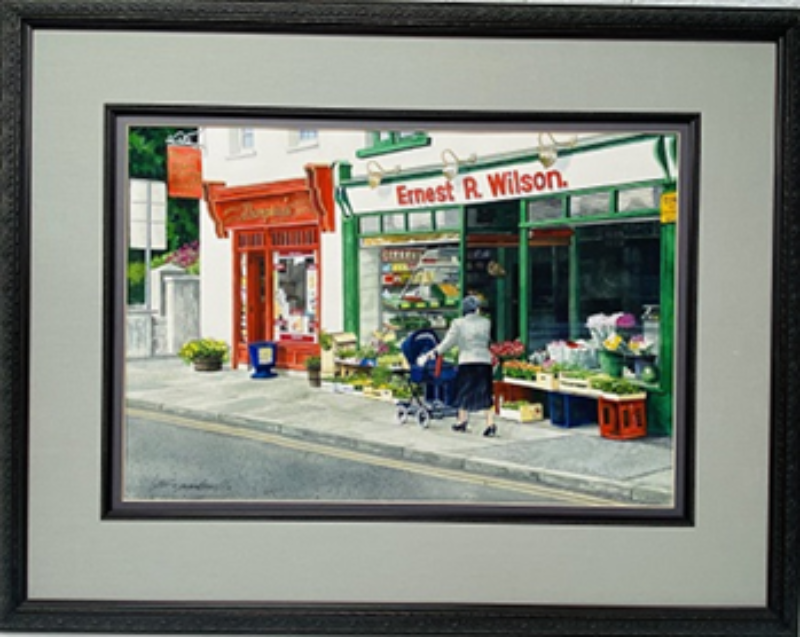 Window Shopping: Hillsborough, N. Ireland- Original Watercolor Painting by Lotus MacDowell, ARtworks, WV. There's something magical about small villages, especially throughout Europe. Lotus MacDowell has captured a moment in time with a scene from a small village in Northern Ireland. The atmosphere is typical Ireland- a clear gray day as a woman walks through the town, pushing a baby carriage and sizing up the flowers in front of the grocery store.